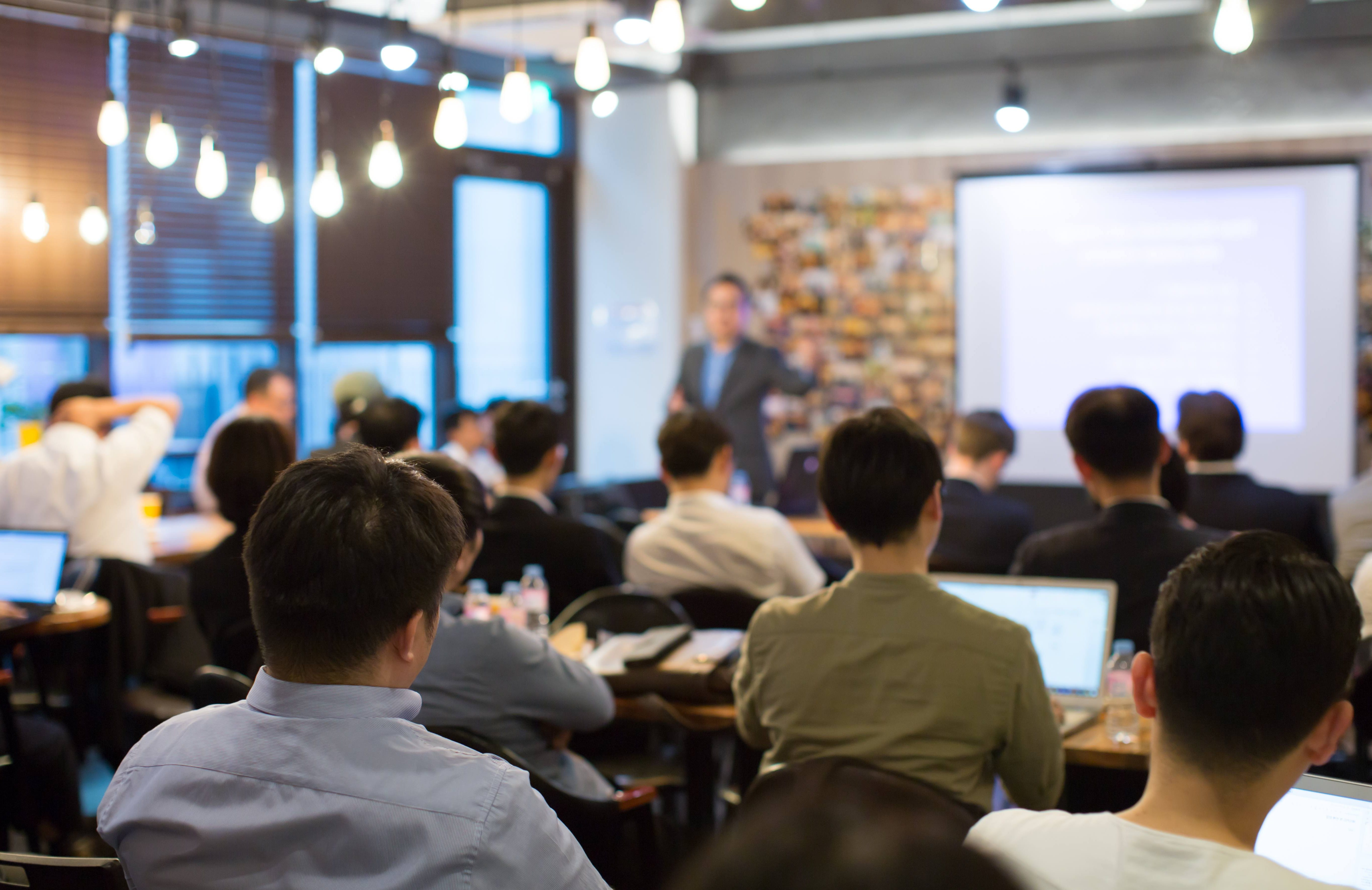 Audience Listens to Lecturer at a Conference Meeting Seminar Training. Group of People Hear Presenter Give Speech . Corporate Manager Speaker Gives Business Technology and Economic Forecast.